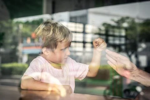 View from outside through window. Little blond caucasian boy play with father Stock-Fotos