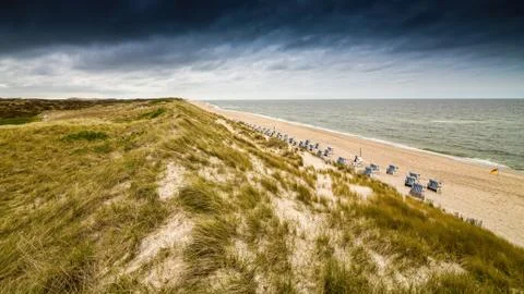 View over the dunes to the ocean to a cloudy sky Stock Photos