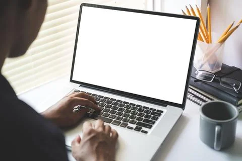 View over man shoulder hands typing on keyboard of laptop computer at  desk.. Stock Photos