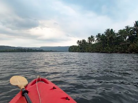 View over the nose of a red plastic canoe boat travelling up River Kong  Stock Photos