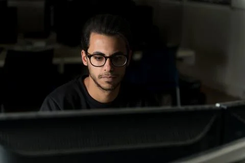View over a screen of the face of a young computer science student working with Stockfoto's