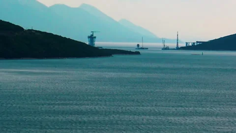 A view over sea bay with bridge construction site in background. Vidéo 155002426