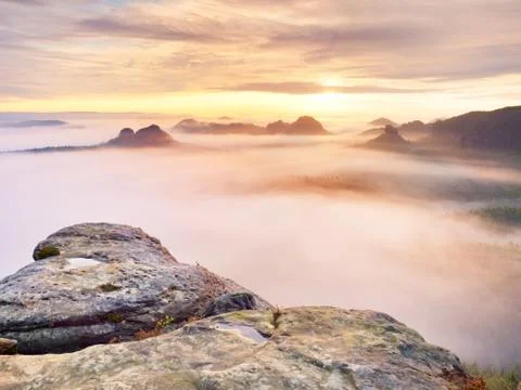 View over sharp sandstone edge into long valley full of first autumnal mist.  Stock Photos