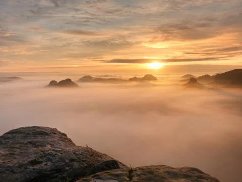 View over sharp sandstone edge into long valley full of first autumnal mist.  Stock Photos