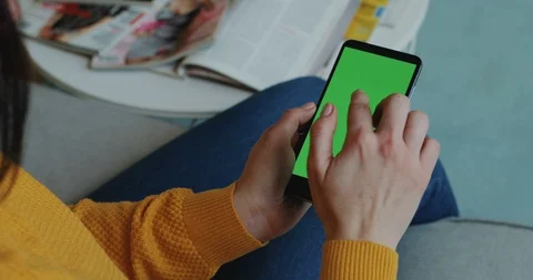 View over the shoulder on the black smartphone with green screen in hands of the Video stock 104223861