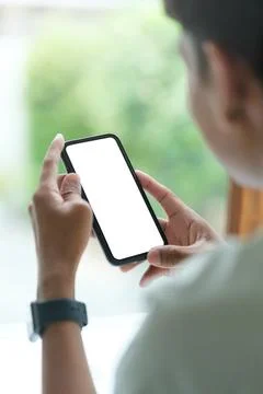 View over shoulder of man hands holding smart phone. Empty screen for your .. Stock Photos