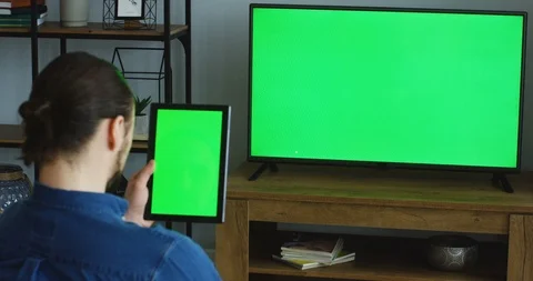 View over the shoulder on the man sitting in the living room, watching TV with Stock-Footage 90208012