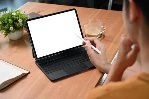 View over shoulder young man using computer tablet on wooden desk. Stock Photos