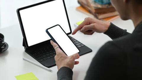 View over shoulder young man working with computer table and using smart phone. Stock Photos