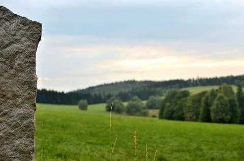 View over stone column wall to meadow and forest. Low depth of field. Stock Photos