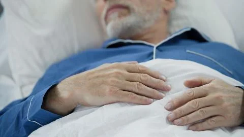 View of overworked wrinkled hands of wise old man peacefully drowsing in bed Stock Photos