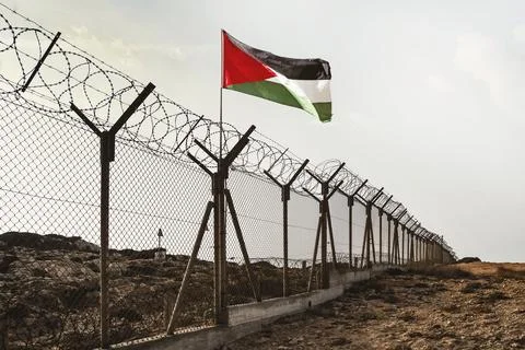 View of Palestinian flag behind barbed wire against cloudy sky in the desert Foto stock
