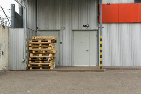 View on pallets, used containers, boxes in front of the door of the warehouse Stock Photos