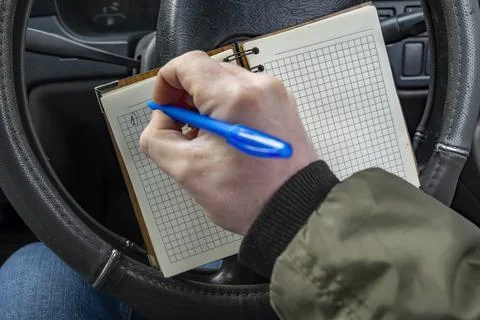 View of paper notebook for notes in the hands of a car driver Stock Photos