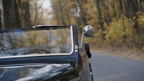 View of part of retro glossy cabriolet on road at autumn forest Video stock 124730959