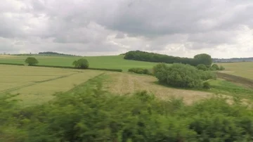 View of passing cloudy rural landscape with green fields and trees from a tra Stock Footage 85762883