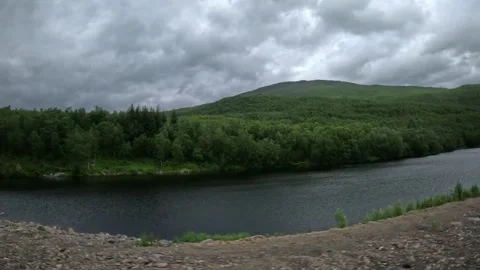 View past lush green forest and calm lake under overcast sky in Senja Norway Stock-Footage 342340383