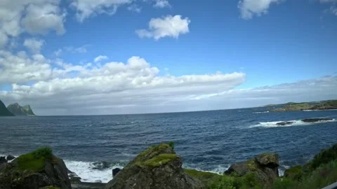 View past open ocean waves, rocky shoreline, and sharp peaks in Senja Norway Vídeo Stock 342340406