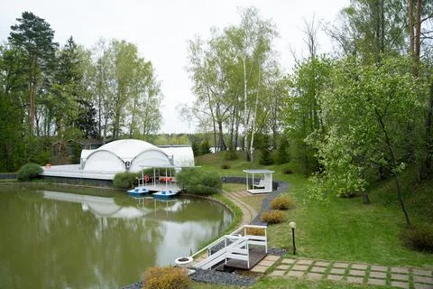 View of the path leading to the pond with a white tent and catamarans Stock Photos