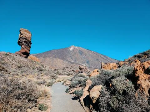 View of a pathway leading to a volcanic mountain with rock formations under.. Stock Photos