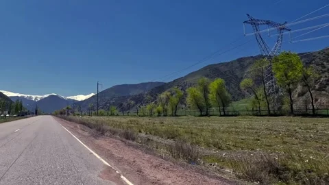 View of the paved road, along which there is a power line and green trees Vídeo Stock 317168374
