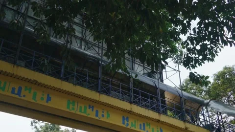 A view of a pedestrian bridge structure with yellow accents and scaffolding surr 库存影片 343372283