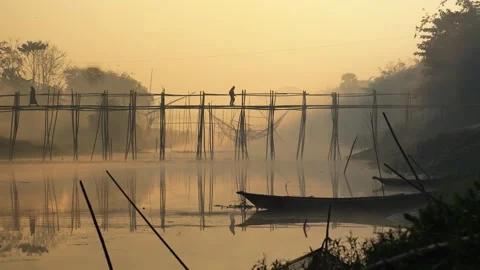 View of people on a bamboo bridge over a river at sunrise, Bangladesh. Видео 335614885