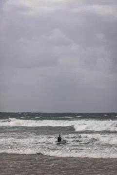 View of people doing surf during a windy day on the beach along the coast in  Stock Photos