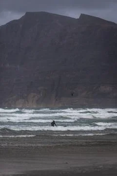 View of people doing surf during a windy day along the coast in Caleta de Fam Stock Photos
