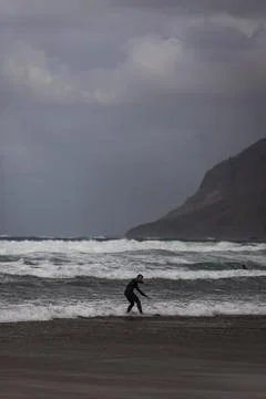 View of people doing surf during a windy day along the coast in Caleta de Fam Stock Photos