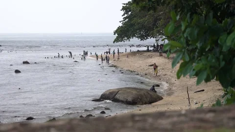 View of people enjoying a sandy beach with large rocks, Sri Lanka. Video stock 335583023