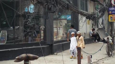 View of people walking past tangled wires in Dhaka, Bangladesh. 스톡 동영상 335557169
