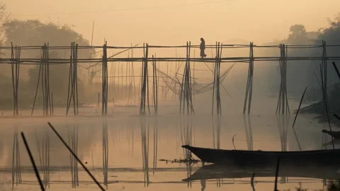 View of a person on a bamboo bridge over a misty river, Bangladesh. Stockbeeldmateriaal 335614180