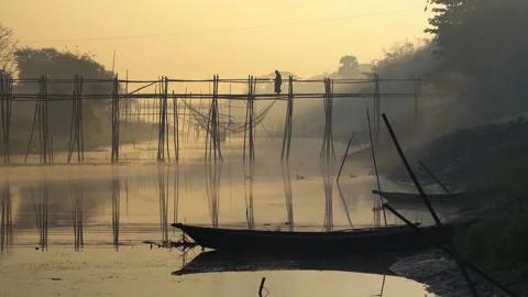 View of a person walking on a bamboo bridge at sunrise, Bangladesh. Vídeos de archivo 335614844