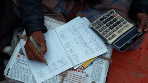 View of a person writing in a notebook with a calculator, Bangladesh. Stock Footage 336427081