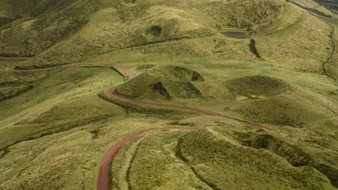View from Pico da Esperan√ßa A red dirt road winds between grassed cinder cones Stock Footage 344532239