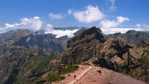 View from Pico do Arieiro showing moving clouds above hikers and rugged volcanic Stock Footage 346648537