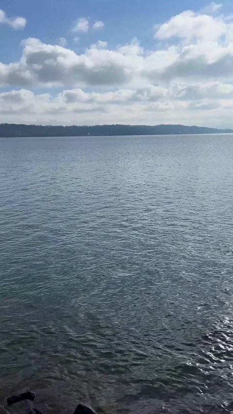 View of a Pier Extending Into the Water With Cloudy Sky and Mountains in the Stock Footage 329234832