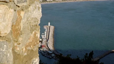 View of pier with lighthouse at end in port or marina of small resort town. View Stock Footage 228702162