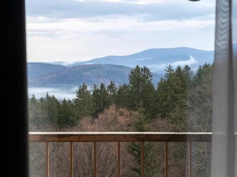 A view of pine forest hills through a window frame at balcony, showing misty Stock Photos