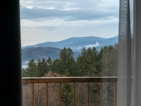 A view of pine forest mountains framed by an indoor window balcony railing, Stock Photos