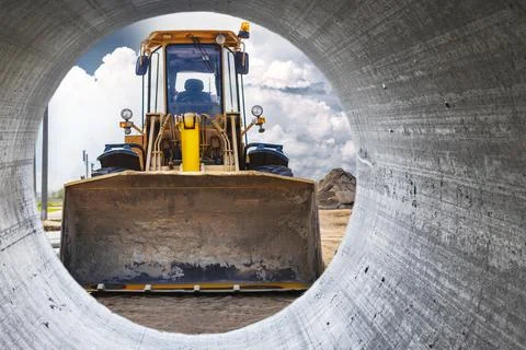 View from the pipe as a bulldozer or loader moves the earth at the constructi Stock Photos