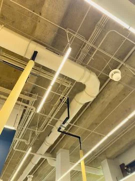 View of pipes, lights, and ceiling in a modern indoor space with long light.. Fotos Stock