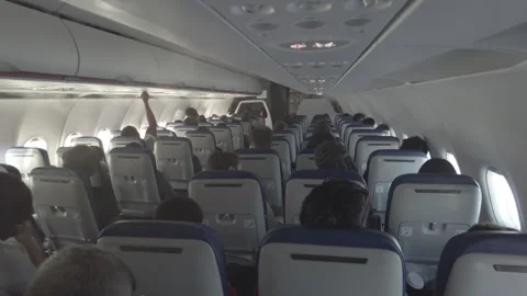 View of a plane interior with multiple sitting passengers and spraying water out Stock Footage 254600232