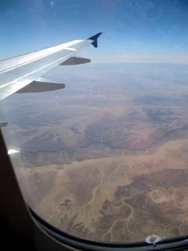 View From the Plane Porthole Overlooking Desert Mountains and Valleys Durin.. Stock Photos