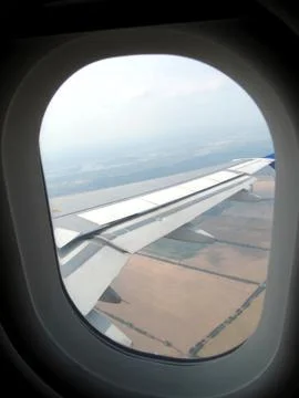 View From a Plane Porthole Showcasing the Wing Above Sprawling Agricultural.. Stock Photos