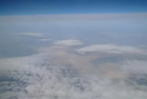 View from the plane window to the clouds and the earth Stock Photos