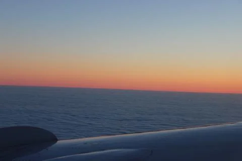 View from the plane into the window. multicolored sky above the wing. fly on  Stock Photos
