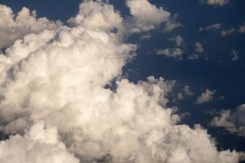 View from plane window of white rain clouds forming on blue sky. Air travel c Foto stock