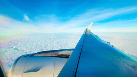 View from the plane window. A wing on a background of blue sky and clouds. .. Stock Photos